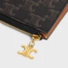 Lot de trois pochettes avec breloques Triomphe en Triomphe Canvas et cuir de veau grainé Lot de trois pochettes avec breloques Triomphe en Triomphe Canvas et cuir de veau grainé