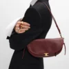 Petit sac Halfmoon Soft Triomphe en cuir d’agneau souple et brillant Petit sac Halfmoon Soft Triomphe en cuir d’agneau souple et brillant