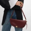 Petit sac Halfmoon Soft Triomphe en cuir d’agneau souple et brillant Petit sac Halfmoon Soft Triomphe en cuir d’agneau souple et brillant